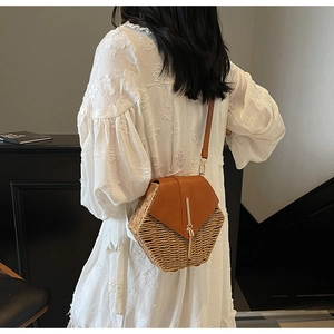 Detail of bohemian straw bucket bag with brown leather flap and golden metal lock closure