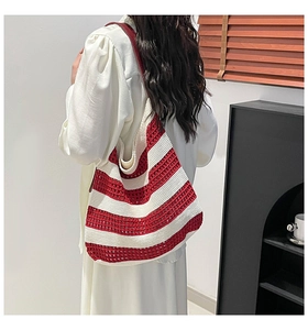 Detail of red and white striped hand-knitted tote bag with elegant red leather shoulder strap