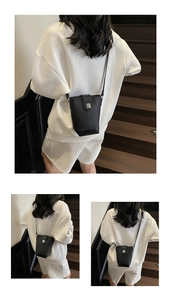 Detail view of a black pebble grain leather mini bucket bag on a white tracksuit model