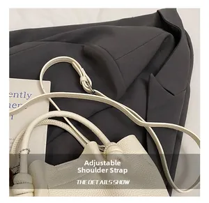 Detail of adjustable knotted shoulder strap on white lychee grain leather bucket bag