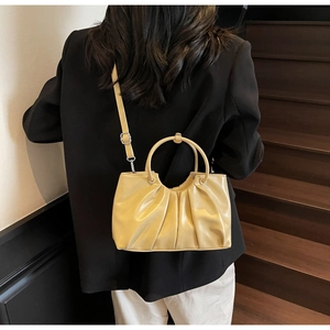 Detail of cream pleated cloud handbag styled with a black blazer on a minimalist model