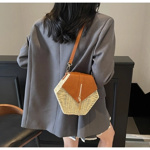 Detail of a hexagonal straw crossbody bag with a brown leather flap and metal buckle