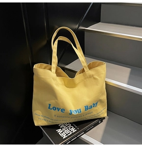 Detail of yellow canvas tote bag with Love You Baby print on a modern staircase