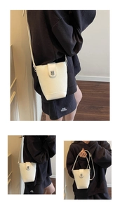 Detailed view of a white lychee grain bucket bag with silver metal lock buckle
