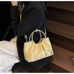 Macro detail of creamy yellow pleated cloud handbag with glossy faux leather texture