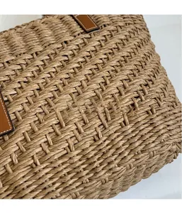 Detail of hand-woven straw tote featuring brown leather trim and fine white stitching