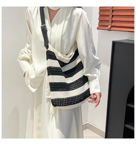 Detail of the woven hollow texture and black leather strap on the striped tote bag