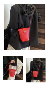 Detail view of a mini red leather bucket bag with silver metal twist lock on a shoulder strap