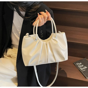 Detail of off-white pleated cloud bag with thick handles and silver hardware