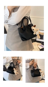Close-up of black lychee leather bucket bag with cute puppy plush charm and shoulder strap