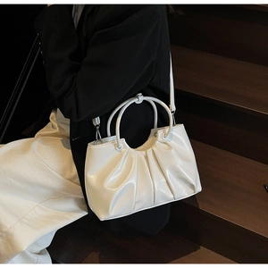 Detailed close-up of white pleated cloud bag with round handle and detachable strap