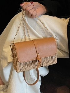 Umhängetasche aus Stroh-Patchwork mit brauner Lederklappe und goldener Kette in Hand