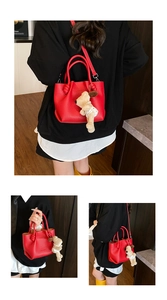 Detail of red lychee pattern leather bucket bag with knotted handle and dog charm