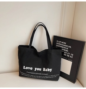Detail view of black canvas tote bag with white Love you Baby artistic lettering