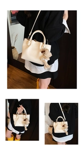 Detail view of cream lychee leather bucket bag with dog charm and knotted handle decor