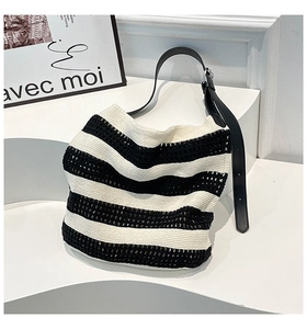 Detail of black and white striped knit hobo bag with adjustable leather shoulder strap