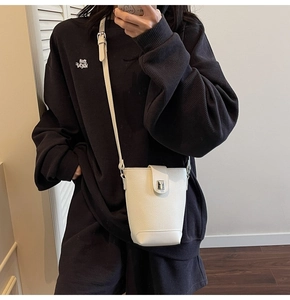 Close-up of white lychee-patterned bucket bag with silver metal lock and adjustable strap