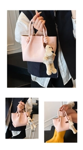 Macro detail of pink lychee textured leather bucket bag with knotted handle and dog charm
