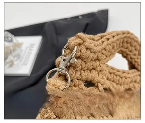 Nahaufnahme des silbernen Karabinerverschlusses und der Webstruktur der khakifarbenen Tasche