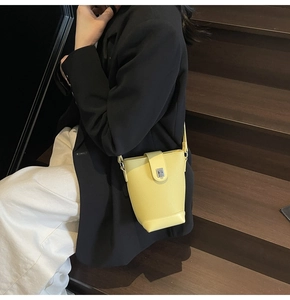 Detail of yellow lychee grain leather bucket bag with silver metal lock and strap