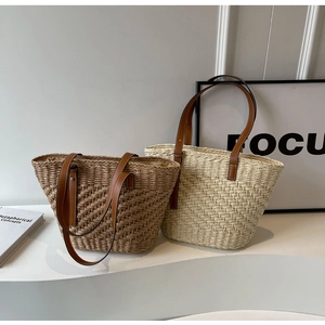 Detail of woven straw tote bags in beige and brown with leather handles for beach vacation