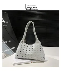 Detail of silver lychee grain leather handbag featuring metallic grommet decorations
