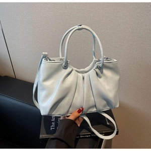 Detail of light blue ruched handbag with oil wax leather texture and magnetic closure