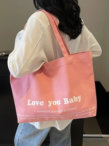Pink canvas tote bag with Love you Baby print worn by a model in casual street style