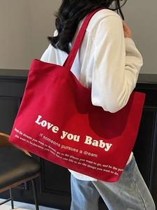Large red canvas tote bag with Love you Baby white print shown in daily use