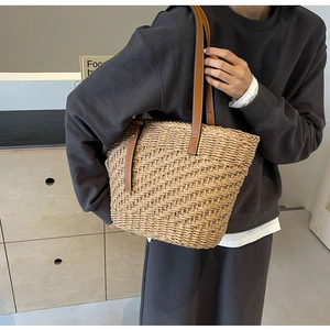 Detailed macro of woven straw texture and premium brown leather straps on a tote bag