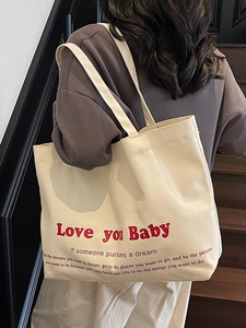 Minimalist cream canvas tote bag with red Love You Baby print shown on female model