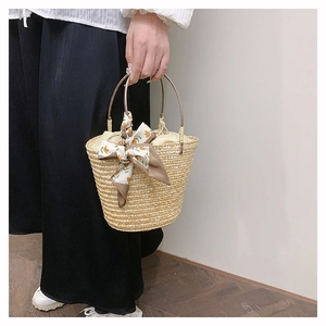Macro detail of hand-woven straw bucket bag with floral silk scarf and ring handles