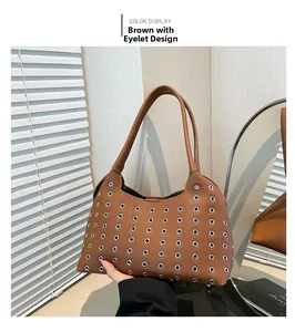 Detailed view of brown leather underarm bag with decorative silver metal eyelets