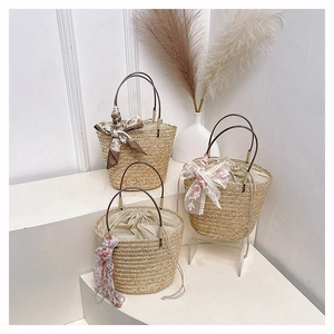 Close-up of woven straw bucket bags featuring leather handles and floral scarf details