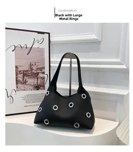 Detail of black pebbled leather handbag featuring large silver eyelet grommet accents