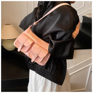 Close-up of pink patent leather shoulder bag with double flap pockets and silver buckles