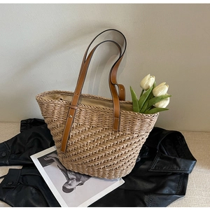 Detail of hand-woven straw tote with premium brown leather straps and metal rivets