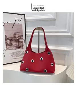 Detail of red pebbled leather handbag with oversized silver metal grommet studs
