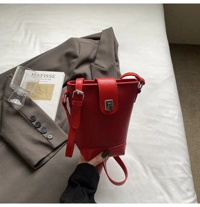 Detail view of red leather bucket bag with silver clasp and adjustable shoulder strap