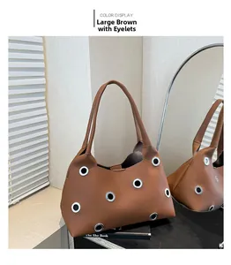 Detailed view of brown litchi grain tote bag featuring oversized silver metal eyelet studs