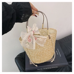 Detail of woven straw bucket bag with floral lace embroidery and round metal handle