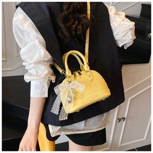 Chic yellow shell bag with lychee texture and lace bow accessory styled on a model