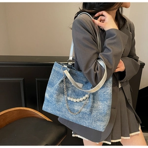 Detail der blauen Denim-Tragetasche mit Perlenketten und silbernen Lederriemen