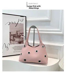Detail view of the pink leather underarm bag featuring large silver metal eyelet accents
