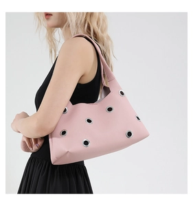 Detailed shot of pink leather underarm bag with large silver eyelets and litchi texture