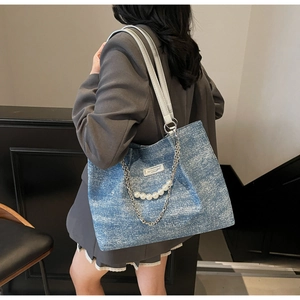Detailansicht der blauen Denim-Tragetasche mit Silberkette und weißen Perlenverzierung