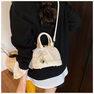 Detail of off-white lychee texture shell bag with lace trim and pearl bow pendant