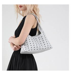 Detail of silver studded underarm bag with hollow eyelets and textured litchi leather