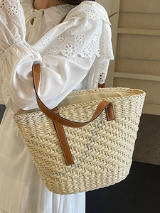Handmade straw tote bag with brown leather straps and spacious interior for beach vacation