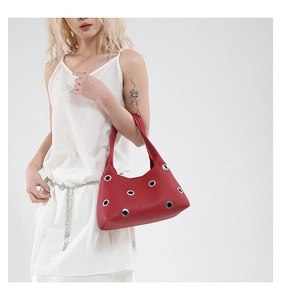 Close-up of red lychee textured underarm bag with silver grommets on a model
